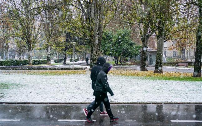 Dos personas caminan bajo la nieve en Gasteiz.