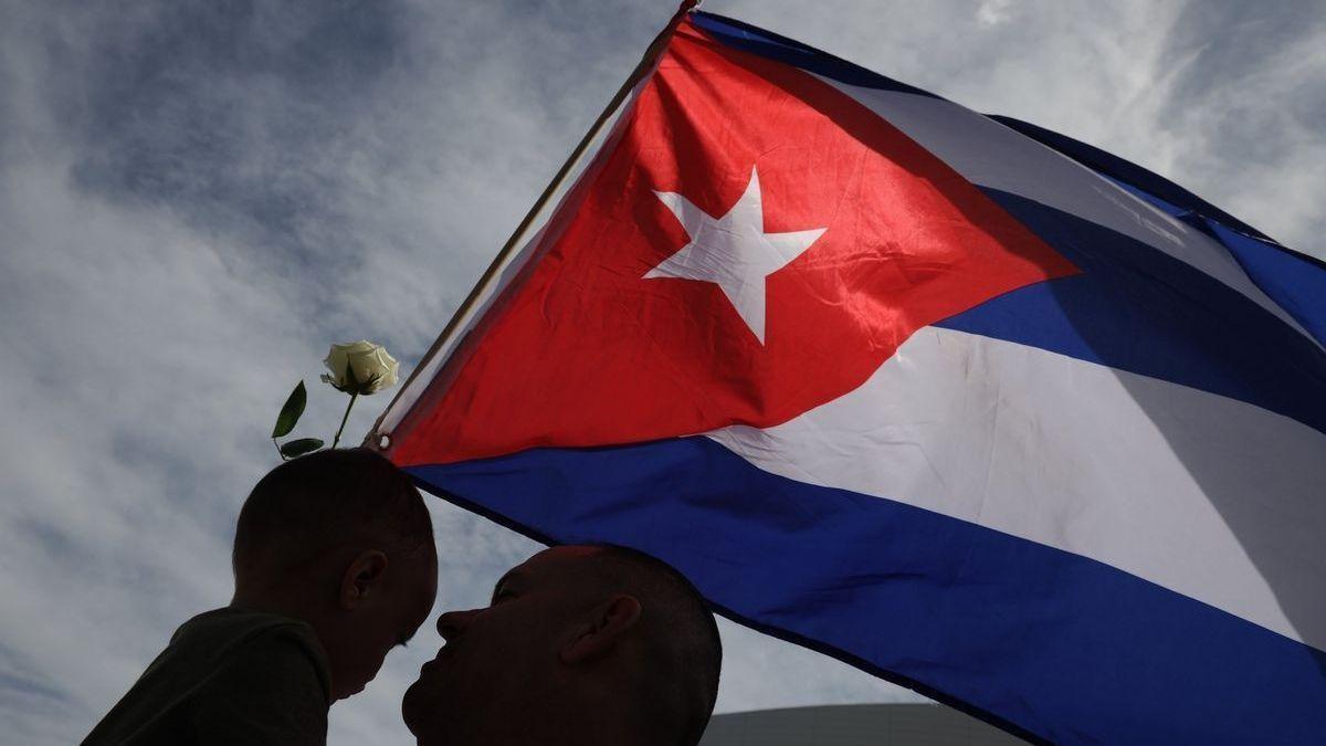 Padre e hijo junto a la bandera de Cuba.