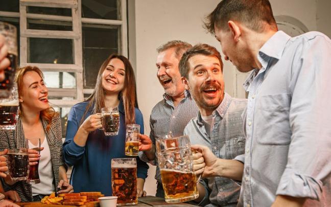 Un grupo de amigos comen y beben en una casa.