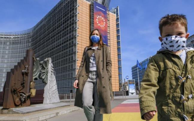 Una mujer y un niño, con mascarilla frente a la sede de la Comisión Europea en Bruselas.