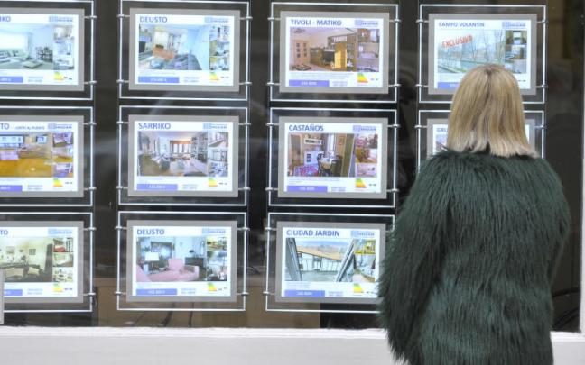 Una mujer observa el escaparate de una inmobiliaria. Una mujer observa el escaparate de una inmobiliaria.