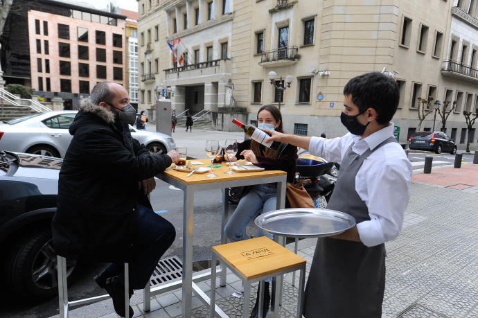 Un camarero sirve vino en una terraza.