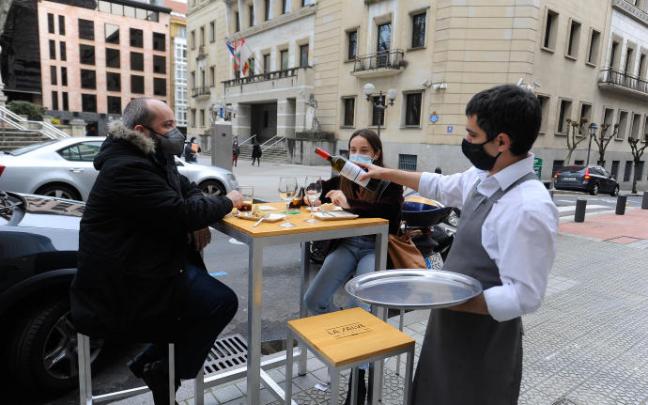 Un camarero sirve vino en una terraza.