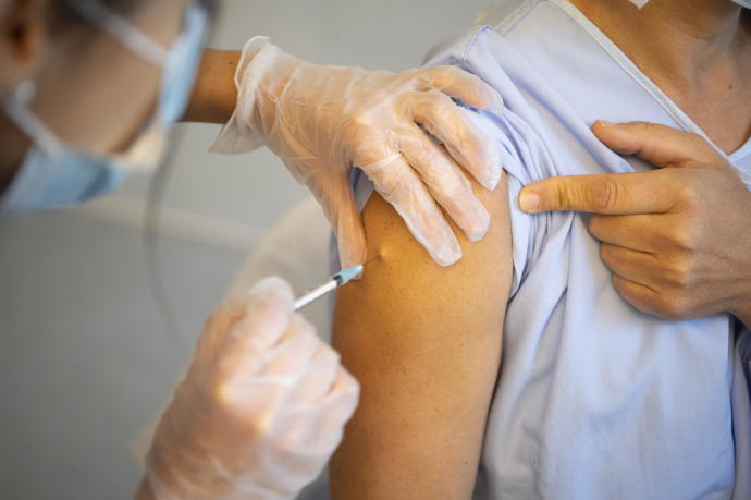 Una enfermera inyecta una dosis de la vacuna a un hombre.