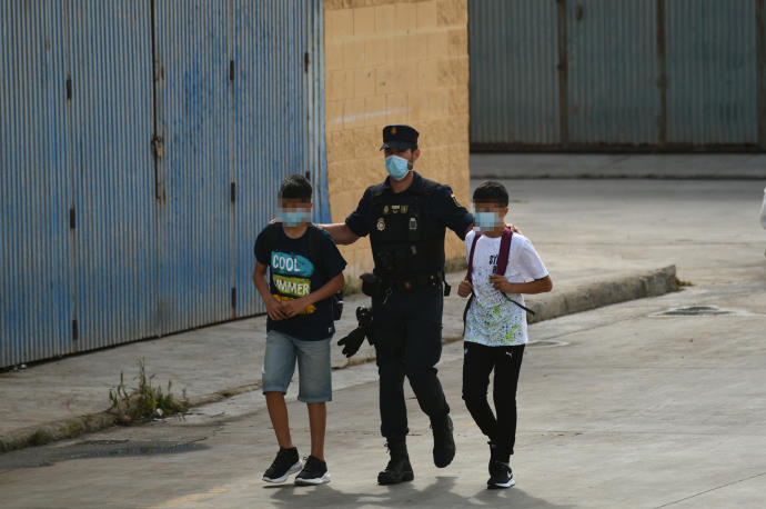 Un policía con dos menores marroquíes en Ceuta.
