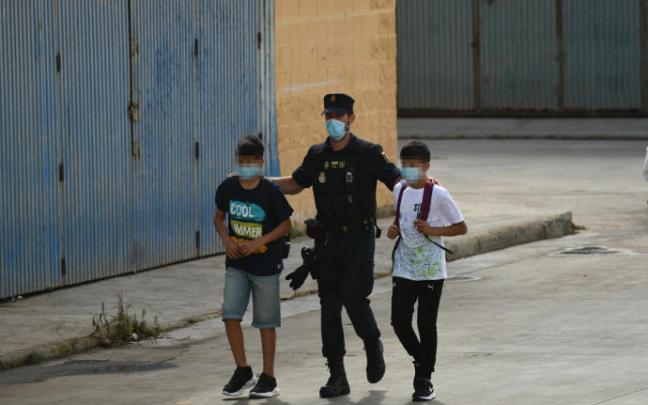 Un policía con dos menores marroquíes en Ceuta. Un policía con dos menores marroquíes en Ceuta.