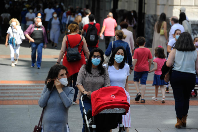 Gente paseando por una calle con mascarilla.