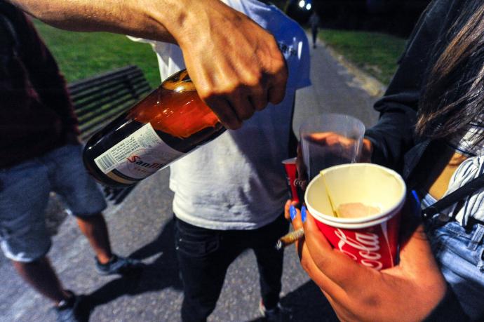 Un grupo de jóvenes bebiendo en la calle.