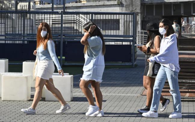 Un grupo de jóvenes pasean con mascarilla.