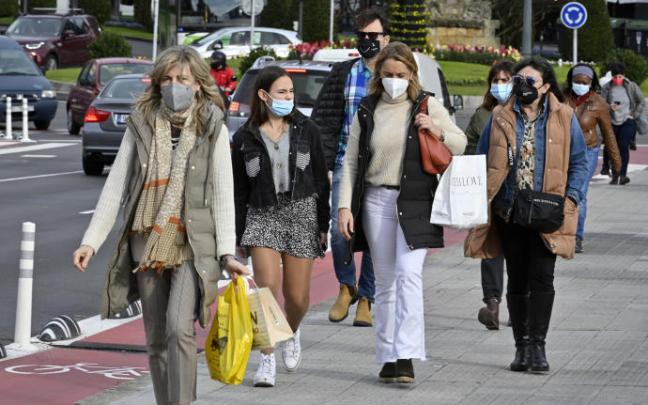 Un grupo de personas, en la calle con mascarillas.