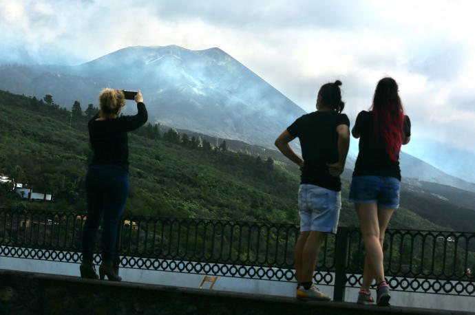 Tres personas observan el volcán de Cumbre Vieja.