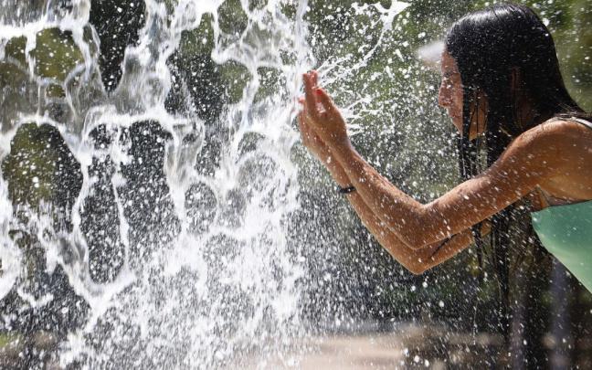 Una joven se refresca en una fuente Una joven se refresca en una fuente
