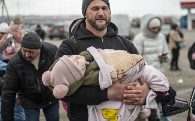 Un hombre con un niño en brazos en el paso fronterizo de Porubne, en el oeste de Ucrania. Un hombre con un niño en brazos en el paso fronterizo de Porubne, en el oeste de Ucrania.