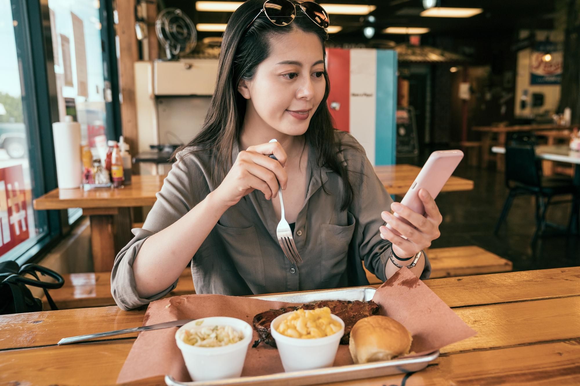 Una mujer consulta el móvil con el tenedor en la mano.