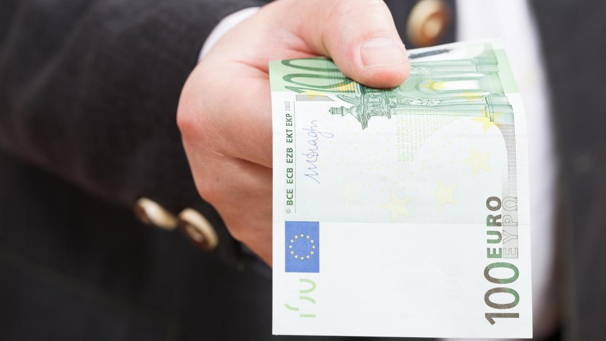 Un hombre paga una compra con un billete de 100 euros.