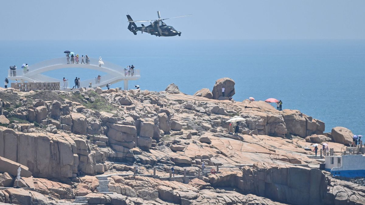 Turistas observan un helicóptero militar chino.