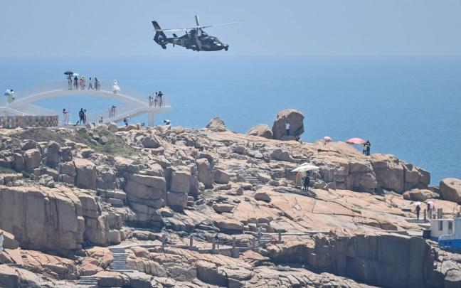Turistas observan un helicóptero militar chino.