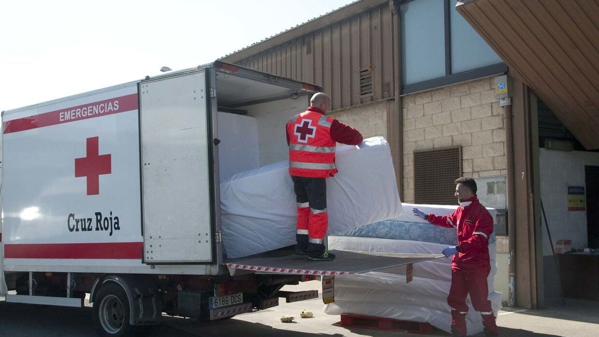 Voluntarios de la Cruz Roja descargan un camión de colchones.