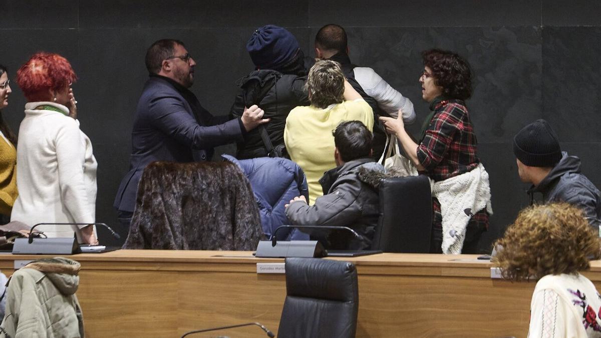 Unai Hualde, presidente del Parlamento foral, y Marisa de Simón, parlamentaria de I-E, tratan de socorrer al hombre que estaba siendo 'detenido' en el Parlamento.