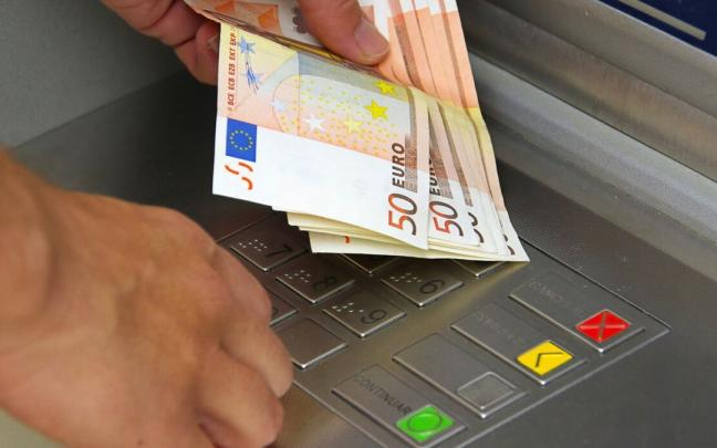 Un cliente saca dinero de un cajero automático Un cliente saca dinero de un cajero automático
