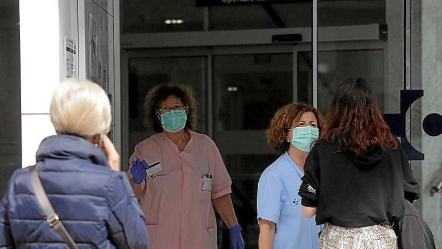 Una enfermera y una auxiliar atienden a varias personas en la entrada del ambulatorio de El Antiguo.