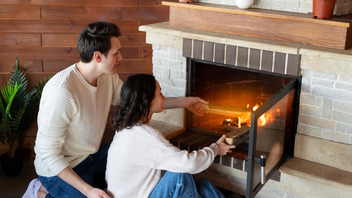 Una pareja, junto a la chimenea encendida en su casa.