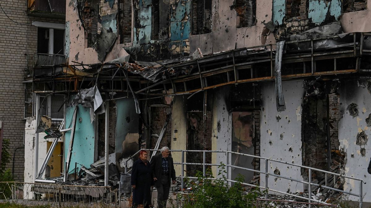 Una pareja de ancianos pasea ante un edificio destrozado en Izium.