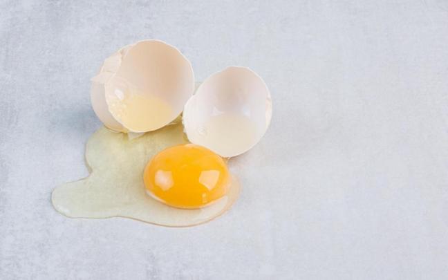 Un huevo con la clara derramada por el suelo y la yema intacta.