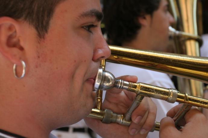 Un joven toca el trombón de varas en una charanga