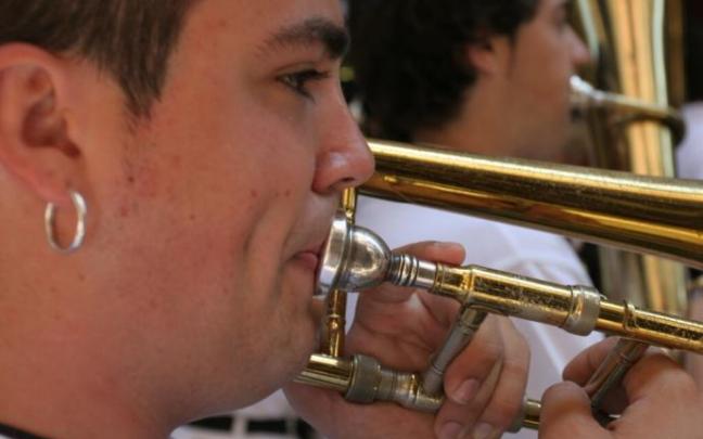 Un joven toca el trombón de varas en una charanga