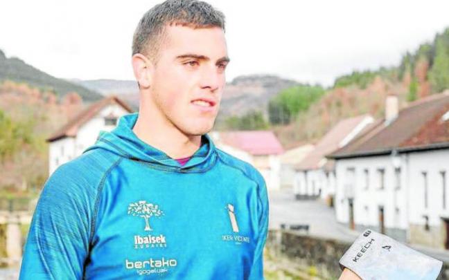El aizkolari Iker Vicente, con el hacha junto al río Anduña en su pueblo, Otsagabia.