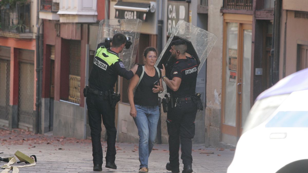 Dos agentes protegen con sus escudos a una vecina el domingo en Nueva Dentro.