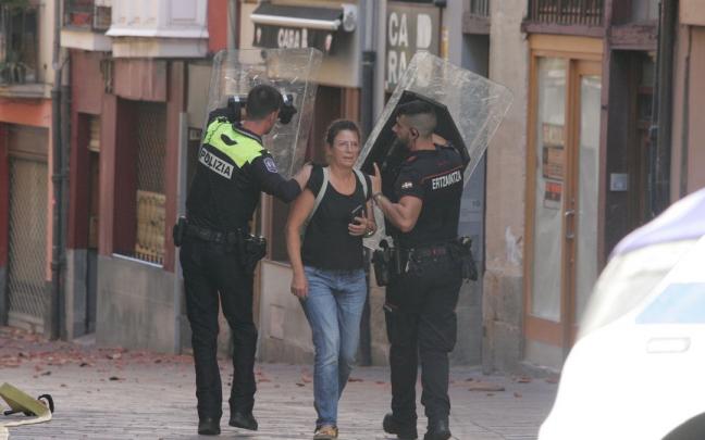 Dos agentes protegen con sus escudos a una vecina el domingo en Nueva Dentro.