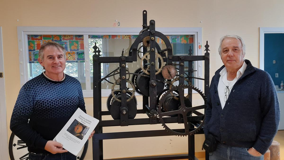 Agustín Lizarralde y Xabier Yeregi junto a la maquinaria del reloj que será restaurado.