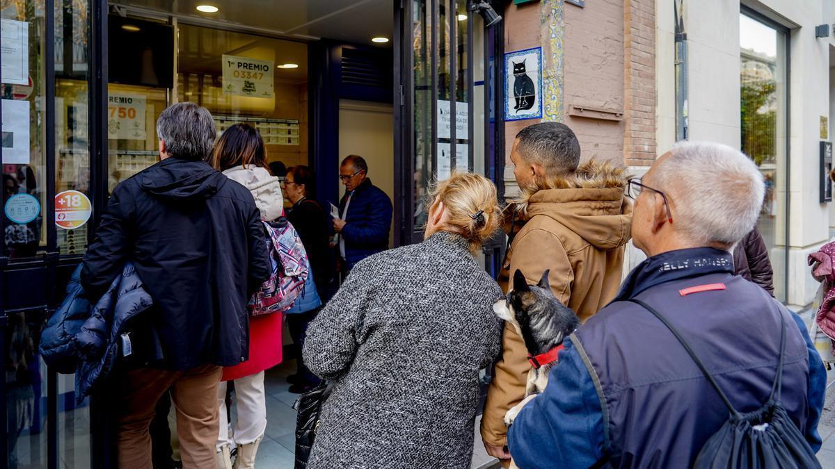 Varias personas hacen cola para comprar lotería de Navidad.