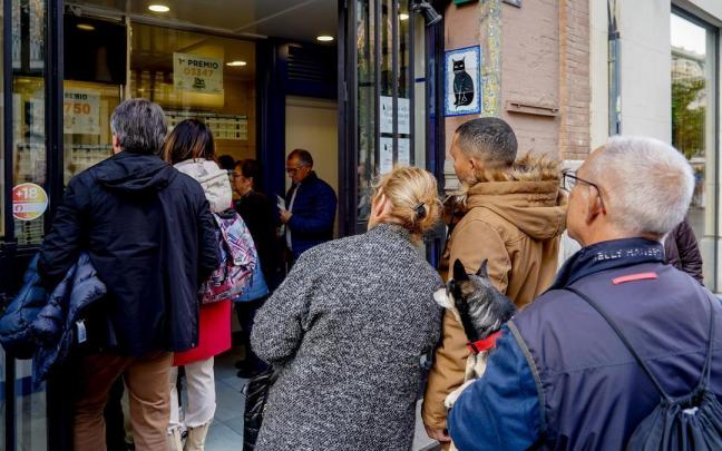 Varias personas hacen cola para comprar lotería de Navidad.