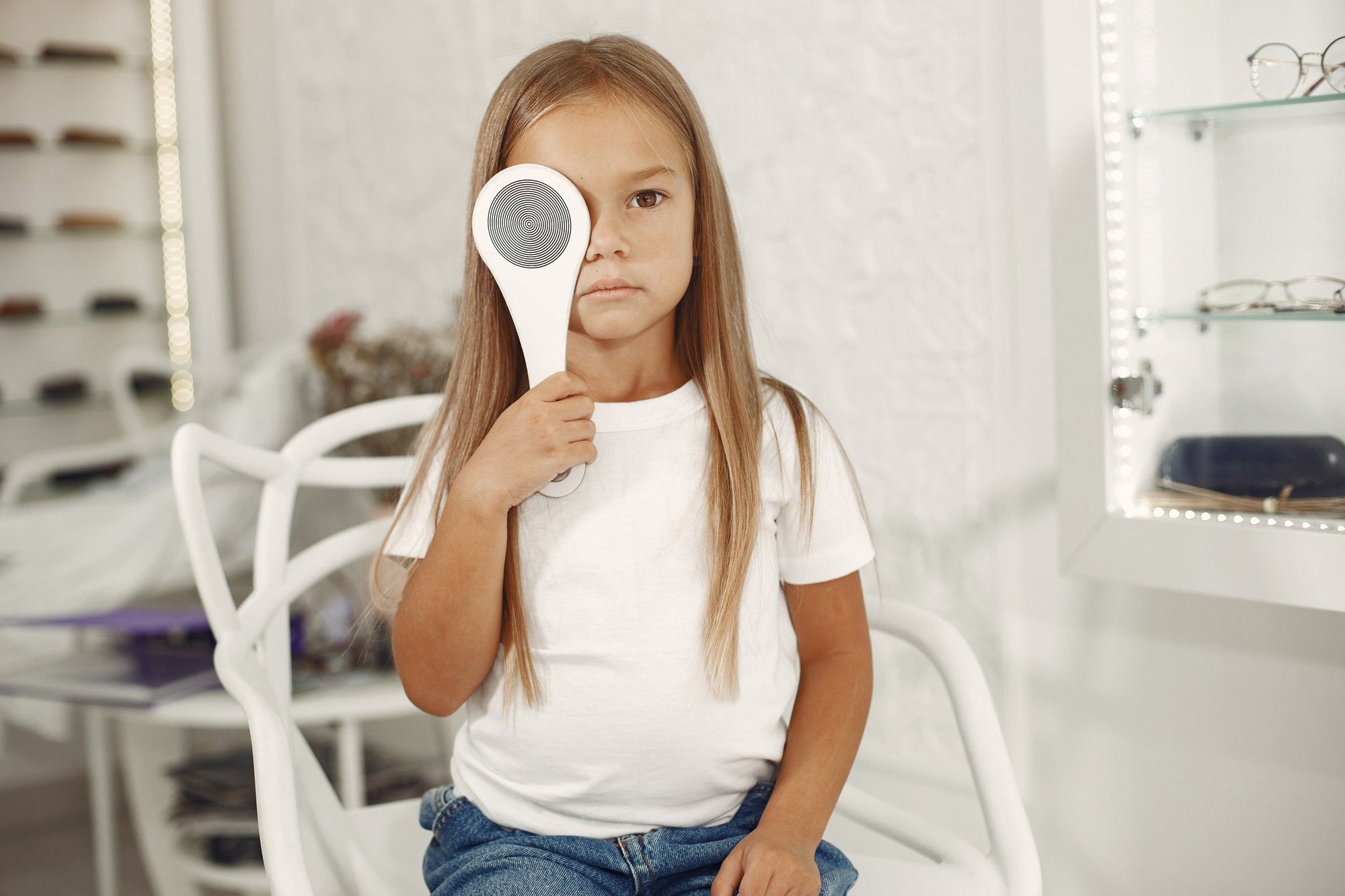 Una niña se tapa un ojo durante un chequeo ocular.