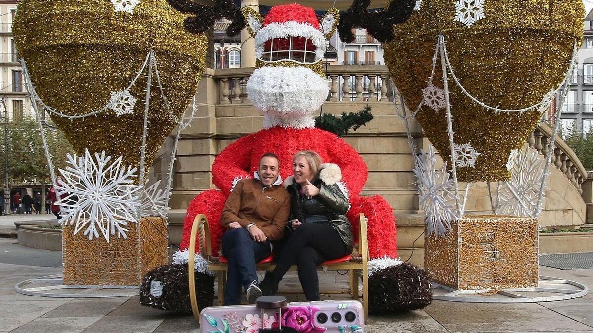 Una pareja posa sonriente en el reno navideño ubicado en la Plaza del Castillo.