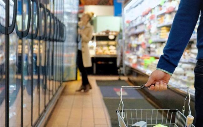 Varias personas comprando en un supermercado con la cesta de la compra. Varias personas comprando en un supermercado con la cesta de la compra.