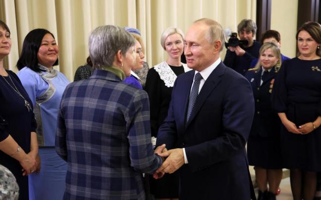 Vladimir Putin saluda a una de las mujeres.