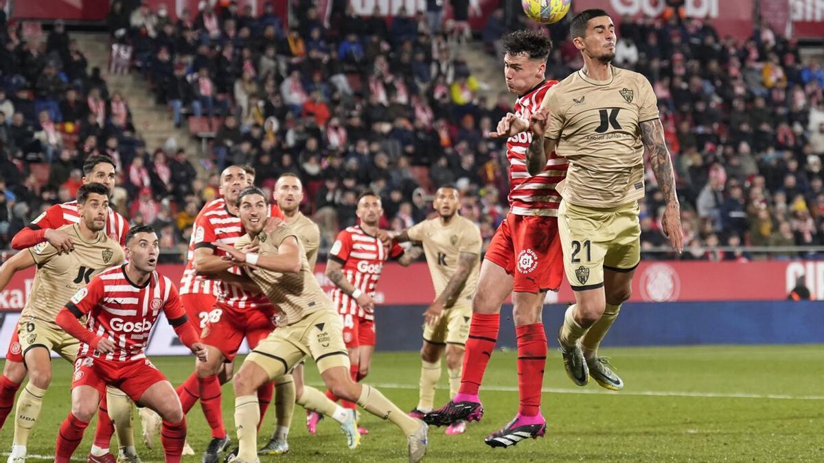 El defensa de la UD Almería Juan Brandáriz "Chumi" (d) salta por el balón con Arnau Martínez, del Girona FC.