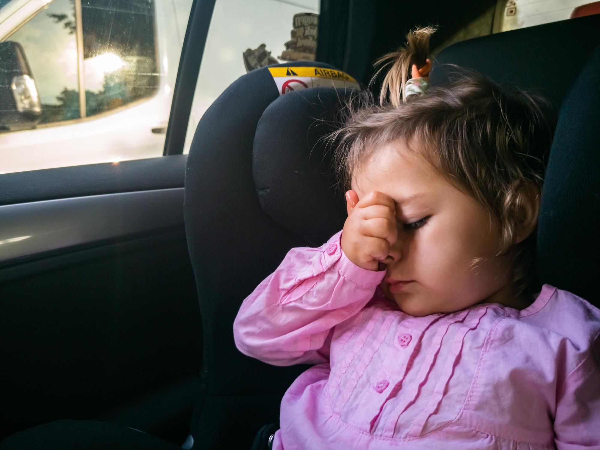Una niña viaja en su sillita con síntomas de mareo.