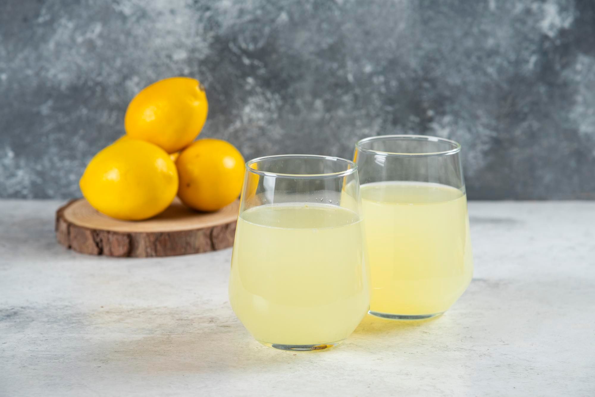 Dos vasos de limonada junto a varios limones.