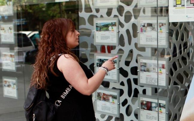 Una persona mira el escaparate de una inmobiliaria. Una persona mira el escaparate de una inmobiliaria.
