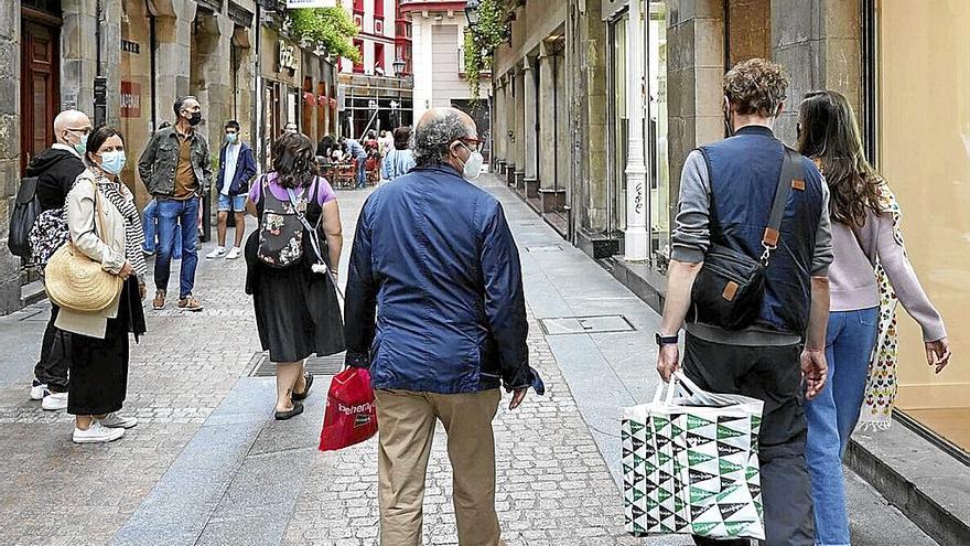 Varios grupos de personas, caminando por una calle del Casco Viejo de Bilbao.