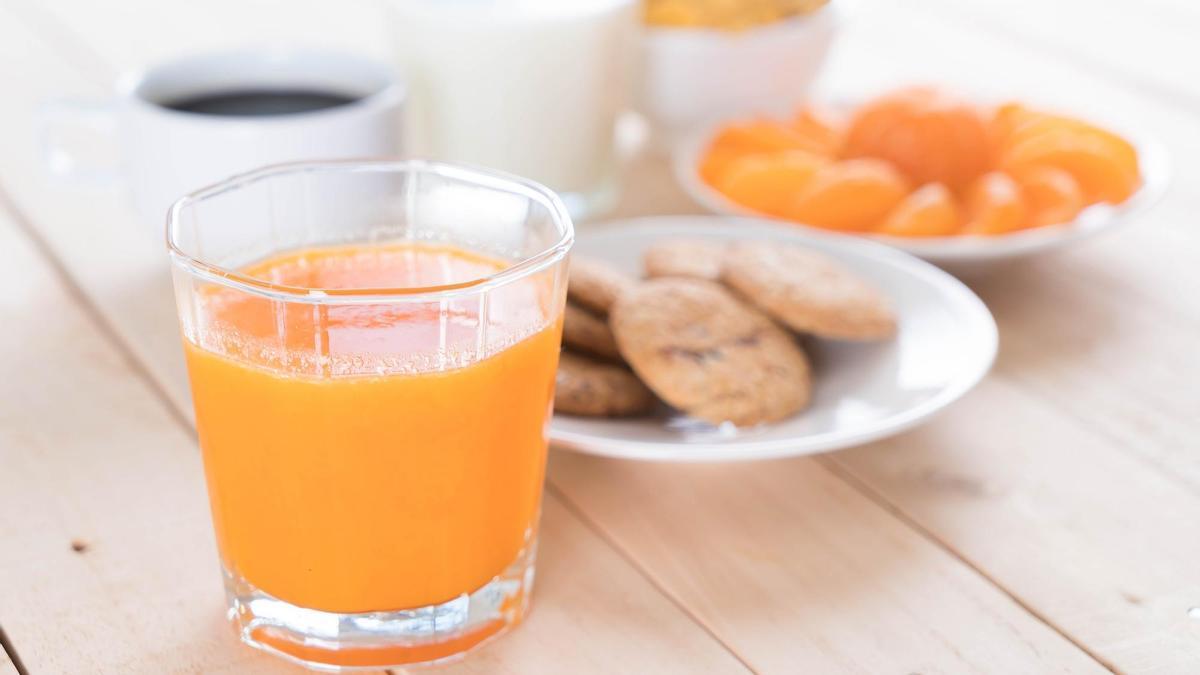 Desayuno a base de café, zumo de naranja, galletas y fruta.