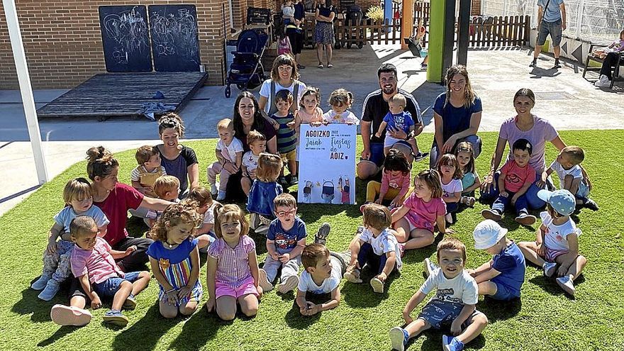 En el jardín de la escuela infantil niñas, niños y el equipo educativo posan con el cartel ganador | FOTO: CEDIDA