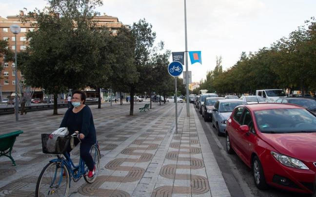 Ciclista circulando por el carril bici de la avenida Barañáin, en mal estado (sin pintura).
