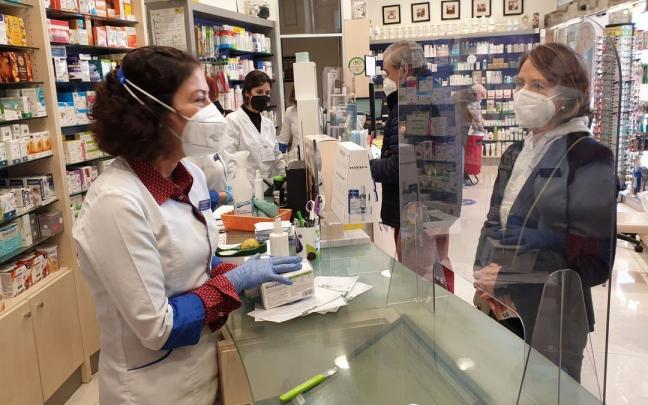 Una farmacéutica entrega varios medicamentos a una mujer. Una farmacéutica entrega varios medicamentos a una mujer.