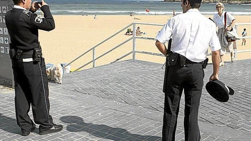 Un agente de la Guardia Municipal toma una fotografía en presencia de otro compañero de trabajo en la playa de la Zurriola.